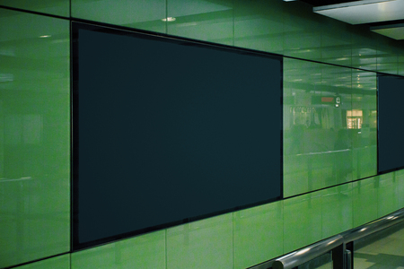Side view of clean black poster in green underground subway station. Commercial and ad concept. Mock...