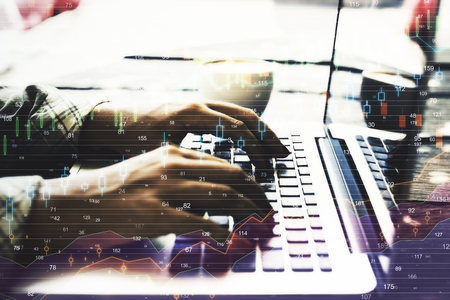 Side view and close up of hands using laptop with forex chart. Invest and finance concept. Double...