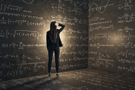 Back view of young businesswoman in concrete corner with mathematical formulas. Complex algorithm and math concept