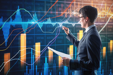 Attractive businessman with document in hand using creative forex chart interface on blurry background. Finance and trade concept. Double exposureの写真素材