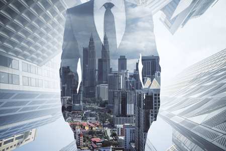 Unrecognizable businessman in suit standing on blurry city background. Career and success concept. Double exposureの写真素材