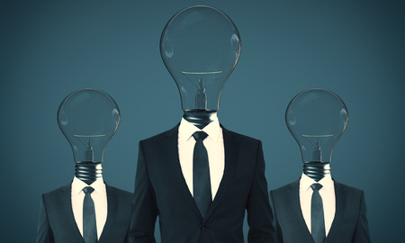 Lamp headed businesspeople standing on blue background. Teamwork and innovate conceptの写真素材