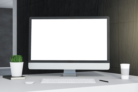 Creative designer desktop with empty computer screen, coffee cup and supplies on wooden wall background. Mock up, 3D Renderingの写真素材
