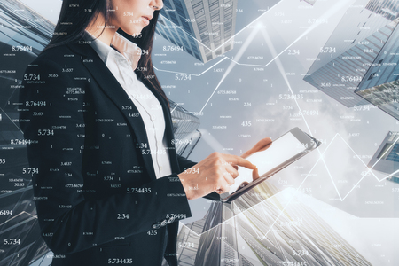 Side view of attractive young businesswoman using tablet on blurry city background with binary code. Communication and software concept. Double exposureの写真素材