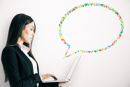 Side portrait of thoughtful young businesswoman using laptop with creative hand gesture speech bubble on white background. Social media, communication and network conceptの写真素材
