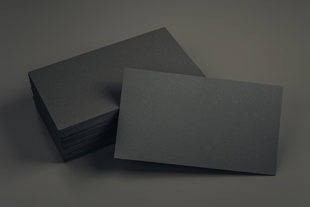 Empty black business card stack on dark desk. Info, address and message concept. Mock up, 3D...