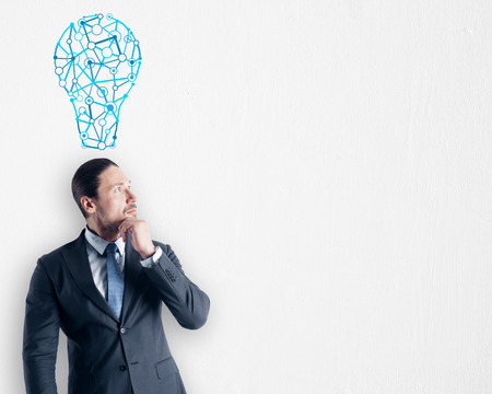 Thoughtful young businessman with light bulb sketch on subtle  background. Idea, innovation, inspire and solution conceptの写真素材