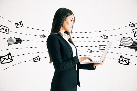 Side view of young businesswoman using laptop with communication sketch on white background. Social network and media conceptの写真素材