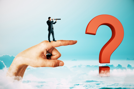 Businessman with telescope standing on abstract hand and red question mark and looking into the distance. Blue sky background. Direction, solution, doubt and success conceptの写真素材