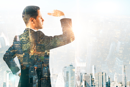Side view of attractive young businessman looking into the distance on abstract city background. Vision and research concept. Multiexposureの写真素材