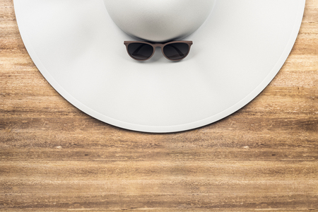 Top view of white designer beach hat and sunglasses on wooden desktop. Holiday, vacation and accessory concept. 3D Renderingの写真素材
