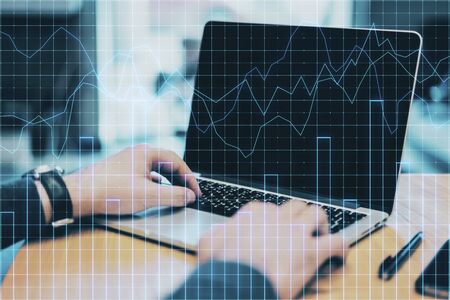 Analytics and fintech concept. Close up of hands using laptop with forex chart on desktop and blurry...