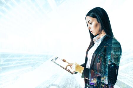 Side view of beautiful young european businesswoman using tablet on blurry city background. Technology and communication concept. Multiexposureの写真素材