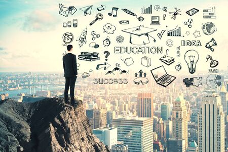 Knowledge and science concept. Businessman standing on cliff with creative education sketch on modern city background. Multiexposureの写真素材