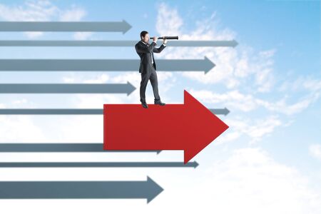 Side view of young businessman with binoculars and arrows on blue sky background. Vision and research conceptの写真素材