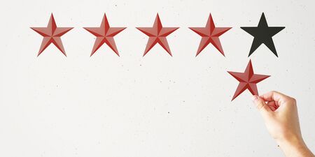 Hand with star rating on subtle background. Evaluation and assessment conceptの写真素材