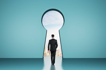 Back view of young businessman in abstract blue interior with keyhole window and sky view. Access and ambition concept.の写真素材