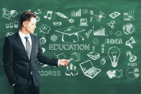 Knowledge and workshop concept. Businessman with creative education sketch on blackboard backgroundの写真素材