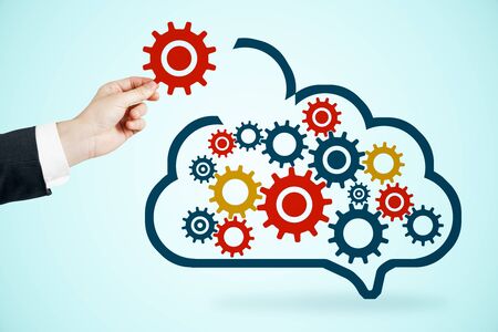 Data storage network technology concept. Businessman hand with creative cloud and cogs on blue backgroundの写真素材