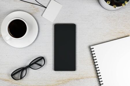 Top view of office workplace with empty smartphone, coffee cup, eyeglasses and supplies. Mock up, 3D Renderingの写真素材