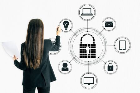 Businesswoman hand drawing creative padlock sketch on white wall background. Protection and password conceptの写真素材