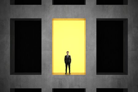 Businessman standing in window of concrete building. Career and success concept.の写真素材
