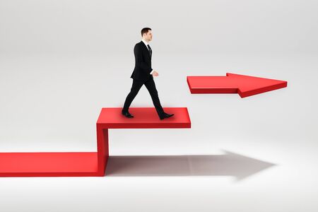 Side view of young businessman walking on broken red arrow. White background. Success and challenge conceptの写真素材