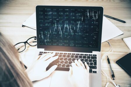 Creative workplace with hands using laptop with forex chart on screen. Trade and market conceptの写真素材