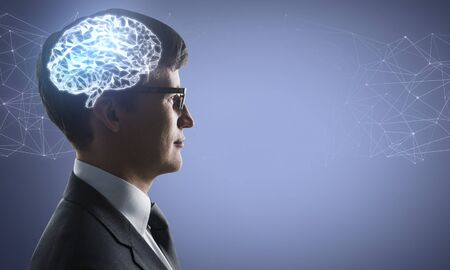 Portrait of young businessman with glowing polygonal brain on purple background. Artificial...