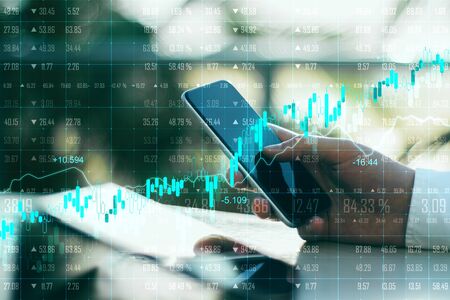 Close up of hands using device with forex chart on blurry background. Technology and stats concept....