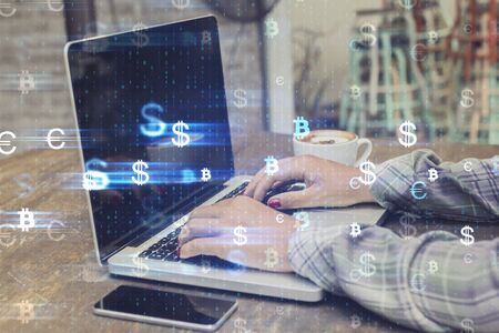 Female hands using laptop placed on desktop with coffee cup and glowing money signs. Cryptocurrency and future concept. Multiexposureの写真素材
