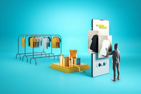 Creative online shopping concept with person in hoodie looking at huge smartphone and racks with clothes on blue background.の写真素材