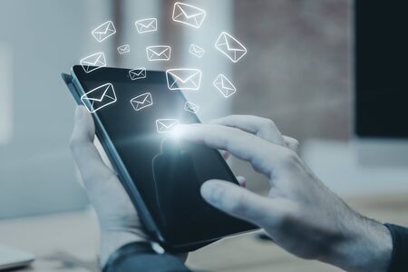 Side view and close up of hand using touchpad with glowing email network on blurry background. E-mail marketing, message and communication concept. Multiexposureの写真素材