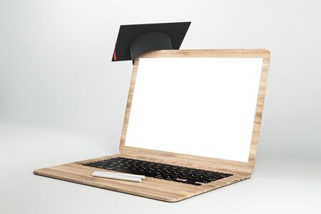 Empty white laptop with abstract tiny graduation cap on grey background. Online education and knowledge concept. Mock up, 3D Renderingの写真素材