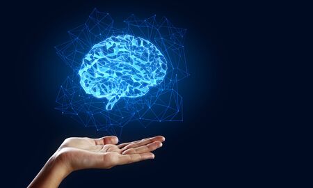 Hand holding creative glowing polygonal brain on blue background. AI and future concept