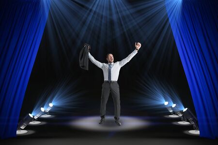 Happy businessman on abstract modern stage with spot light and blue curtains. Success, leadership and star concept.の写真素材