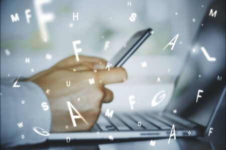 Side view of businessman hands using laptop and smartphone with abstract letters. Communication and network concept. Multiexposureの写真素材