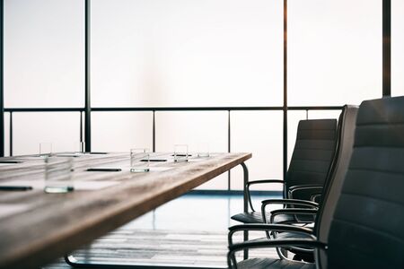 Close up of wooden conference table ready for meeting with glasses, pens and blank sheets in the...