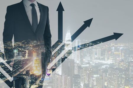 Growth concept with multiexposure of businessman and arrows at night city background.の写真素材