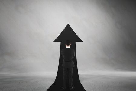 Career advancement concept with businessman staying midst black upward road-arrow at abstract...