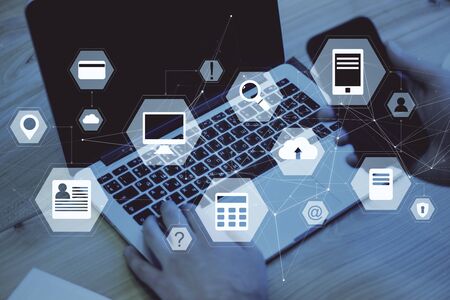 Hand using laptop with abstract digital business interface on desktop background. Innovation and cloud computing concept. Double exposureの写真素材
