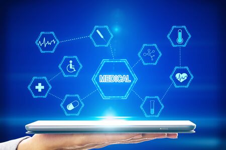 Close up of hand holding tablet with creative medical interface on blue background. Medicine and science conceptの写真素材