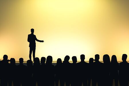 Businessman giving speech in front of backlit audience on light yellow background. Speaker and motivation conceptの写真素材