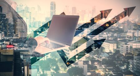 Unrecognizable businessman using laptop on abstract city background with digital arrows. Growth and career development concept. Multiexposureの写真素材