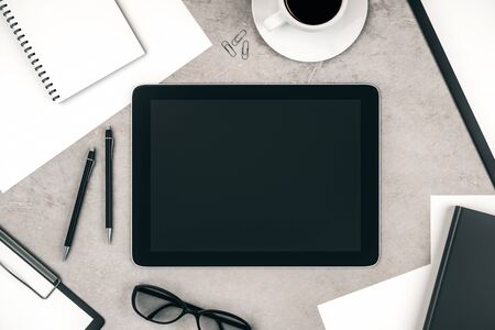 Top view of concrete desktop with empty tablet, coffee cup and supplies. Mock up, 3D Renderingの写真素材