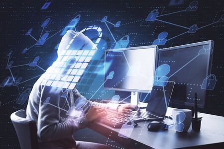 Hacking and login concept. Hacker at desktop using laptop with glowing padlock hologram in dark...