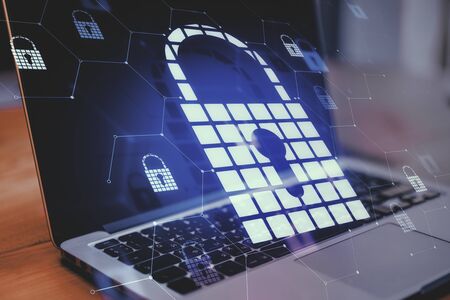 Close up of laptop with abstract glowing padlock hologram on blurry background. Web safety and protection concept. Double exposure の写真素材