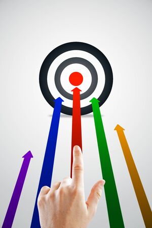 Hand pointing at creative background with bulls eye and colorful arrows.の写真素材