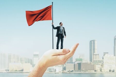 Abstract hand holding businessman with red flag on blurry New York city background. Leadership and success concept の写真素材