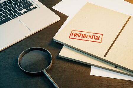 Top view of wooden desk with laptop, magnifier and secret files. Confidential information and detective concept. 3D Renderingの写真素材